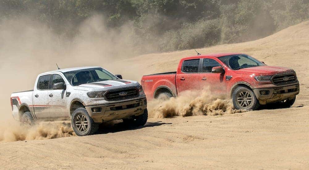 Two Ford trucks, a white 2021 Ford Ranger Tremor XLT and a red 2021 Ford Ranger Tremor Lariat are racing through the sand.