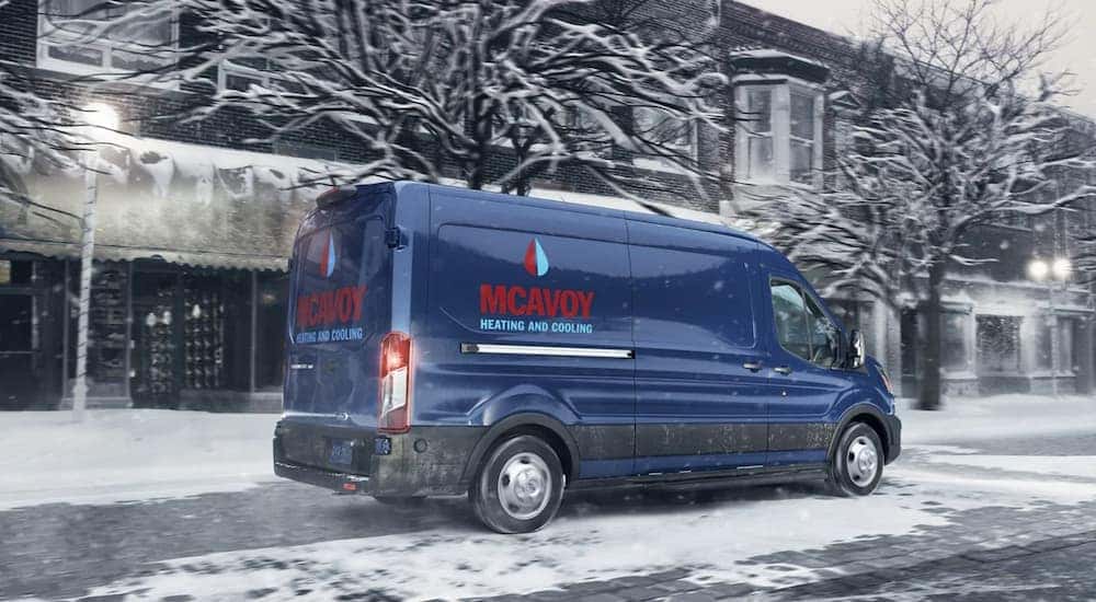 A blue 2020 Ford Transit Cargo is driving over a snowy road.