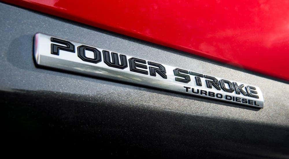 A closeup shows the Powerstroke badging on a red 2020 Ford F-150 at a Ford diesel truck dealer.
