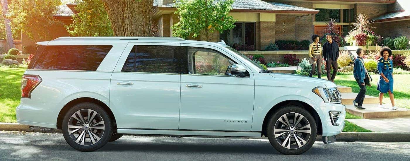 A white 2021 Ford Expedition is shown from the side with a house and family in the background.