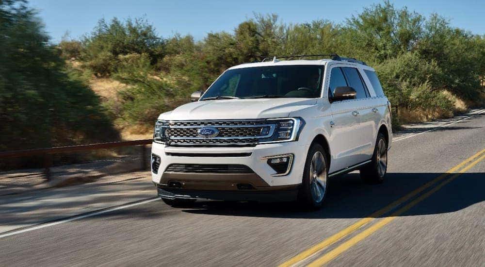 A white 2021 Ford Expedition King Ranch is driving on a highway.