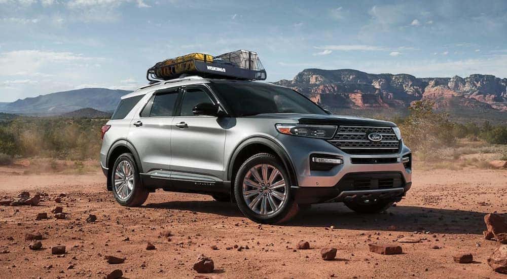 A silver 2021 Ford Explorer is parked on red dirt in front of mountains.