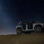 A silver 2021 Ford Bronco Wildtrack is in the desert on a starry night.