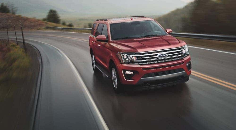 A dark red 2020 Ford Expedition is driving on a winding road.