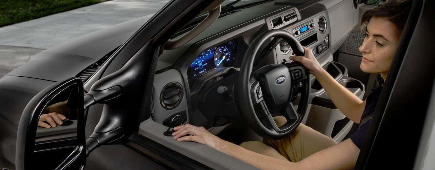 A close up shows a woman looking in the side mirror of a black 2022 Ford E-Series Cutaway.