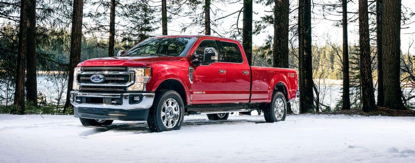 A red 2021 Ford F-250 King Ranch is parked the snow in the woods.