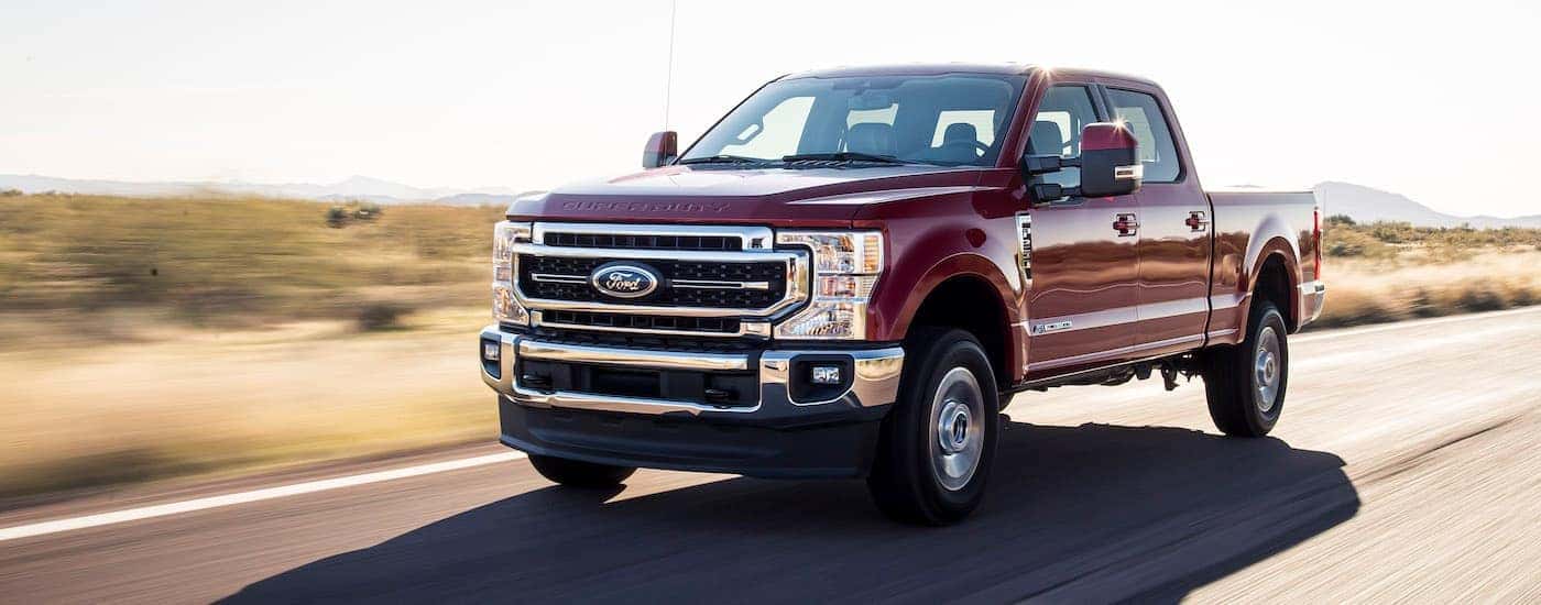 A maroon 2021 Ford F-250 Lariat Ultimate is shown from the side driving down an empty highway.