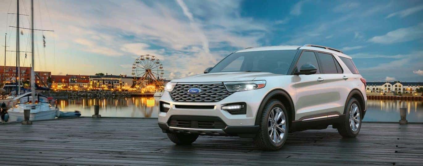 A white 2021 Ford Explorer is shown with an amusement park and lake in the background.