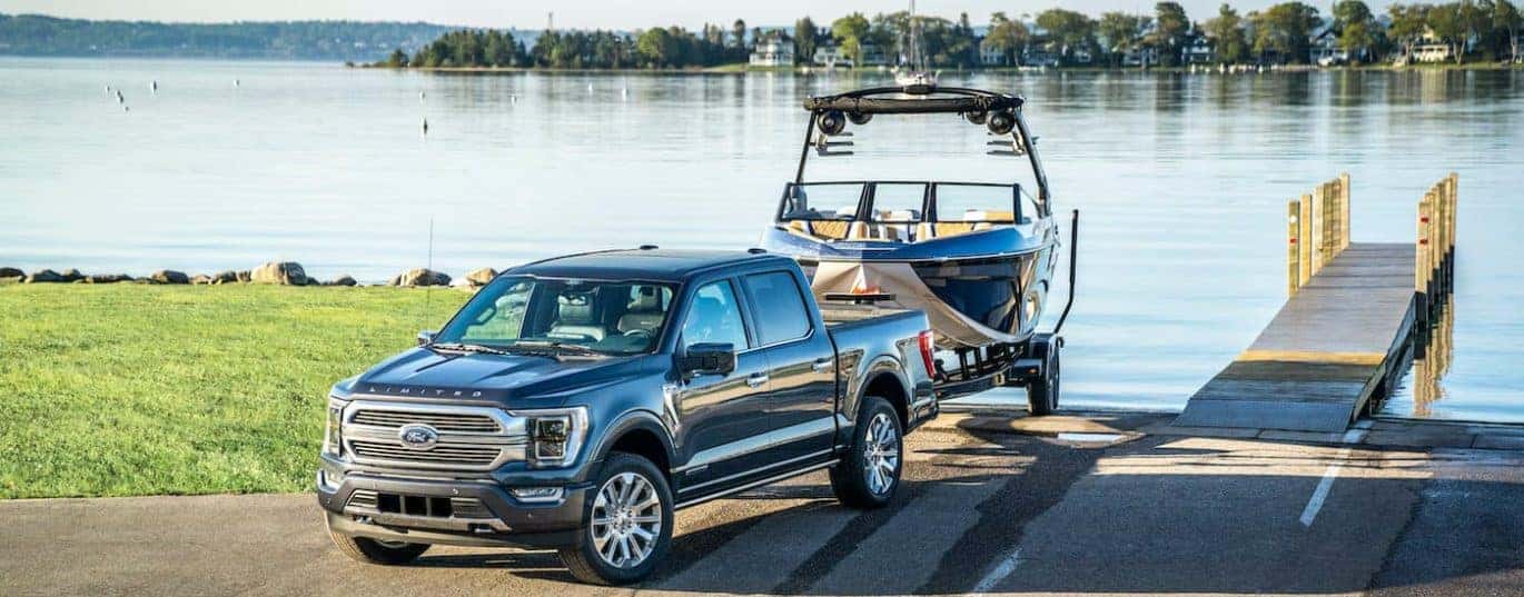 A black 2021 Ford F-150 is shown backing a boat into a lake after winning the 2021 Ford F-150 vs 2021 Nissan Titan showdown.