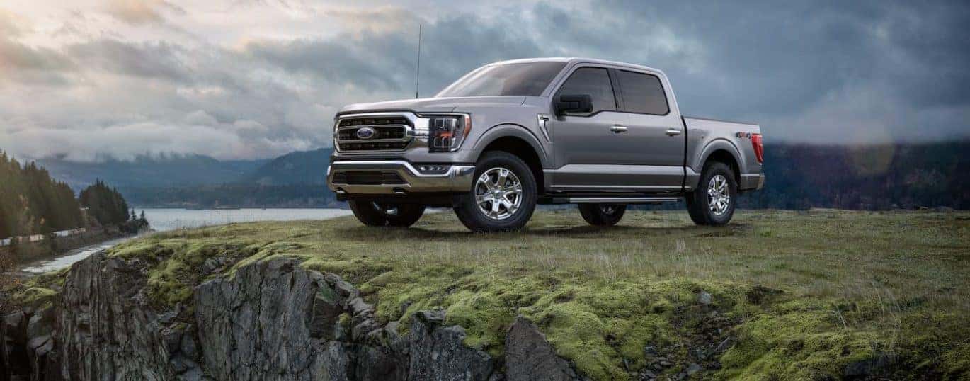 A grey 2021 Ford F-150 is parked next to a lake after winning the 2021 Ford F-150 vs 2021 Ram 1500 comparison.