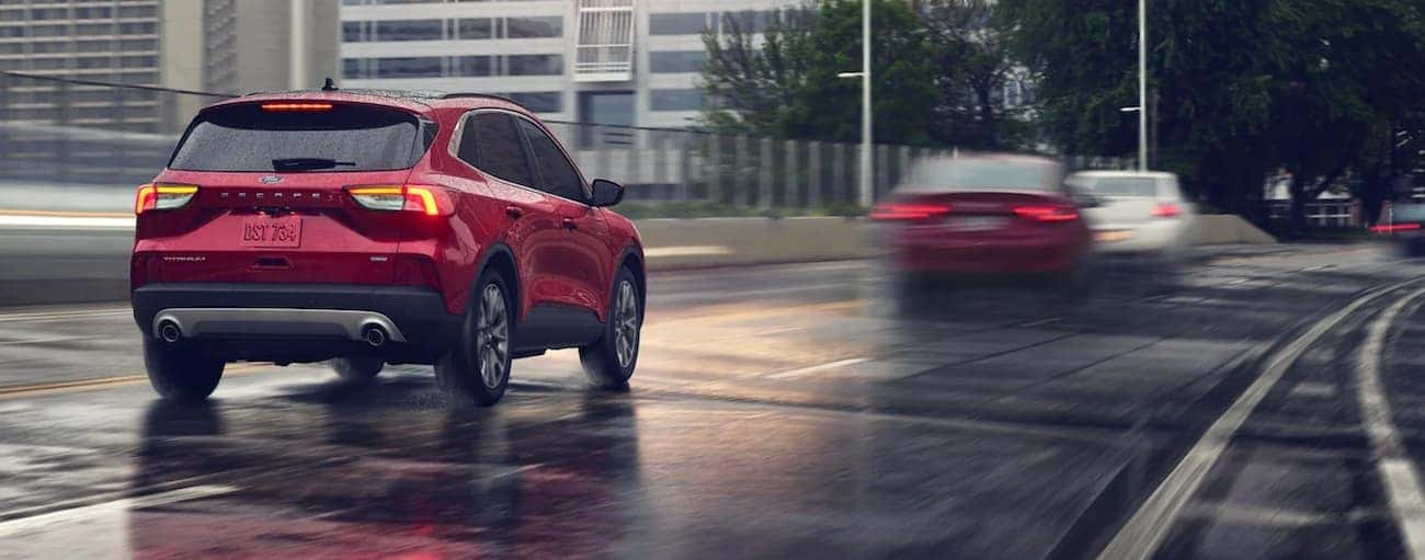A red 2021 Ford Escape is driving on a rainy highway road.