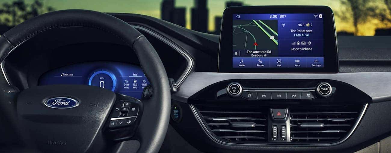 The interior of a 2021 Ford Escape shows the steering wheel and infotainment screen.