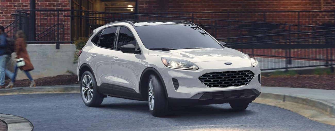 A white 2021 Ford Escape is driving on a one way road during a 2021 Ford Escape vs 2021 Chevy Equinox comparison.