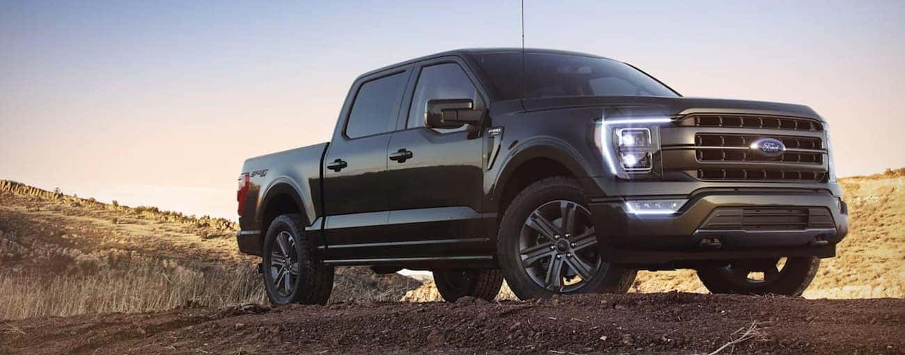 A black 2021 Ford F-150 is shown from a low angle parked in a field during a 2021 Ford F-150 vs 2021 Toyota Tundra comparison.