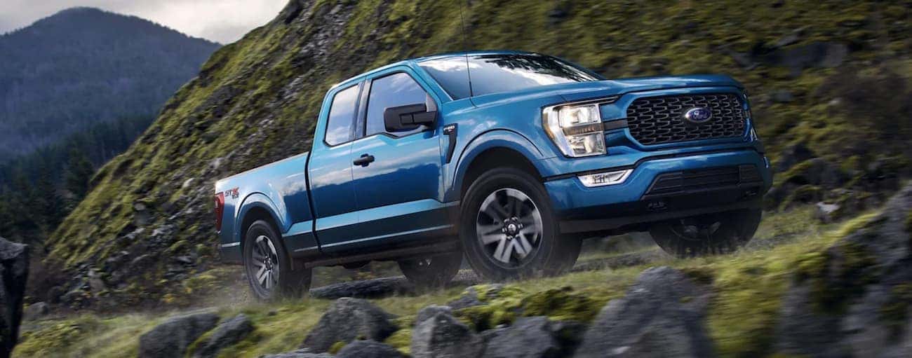 A blue 2021 Ford-150 is shown driving in the mountains after winning a 2021 Ford F-150 vs 2021 Toyota Tundra comparison.
