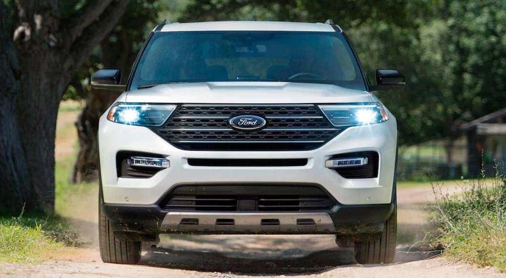 A white 2021 Ford Explorer is shown from the front driving down a dirt road.
