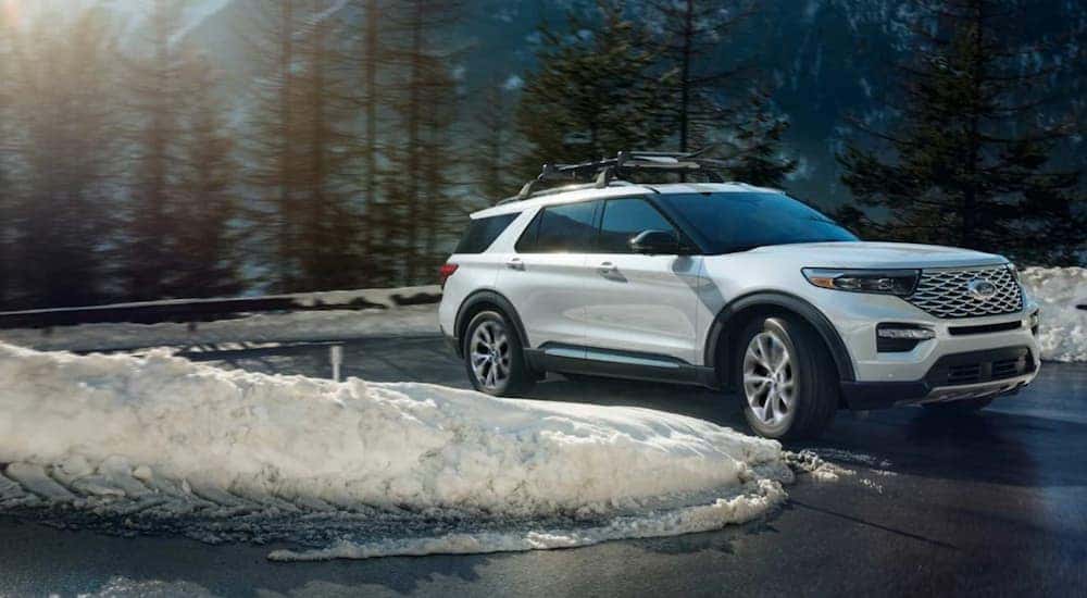 A white 2021 Ford Explorer is shown driving around a curve after leaving a Ford Explorer ST dealer.