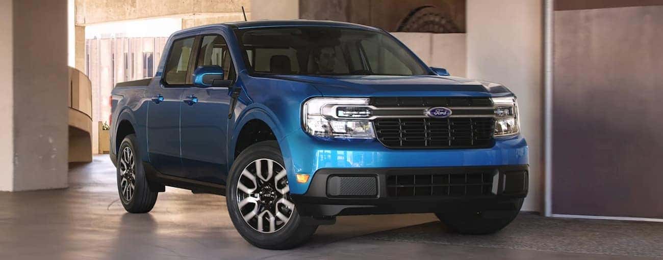A blue 2022 Ford Maverick is shown parked in a modern gallery.
