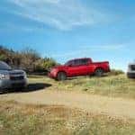 A blue, a red, and a silver 2022 Ford Maverick are shown parked near a dirt path.