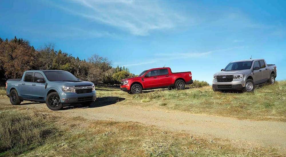 A blue, a red, and a silver 2022 Ford Maverick are shown parked near a dirt path.