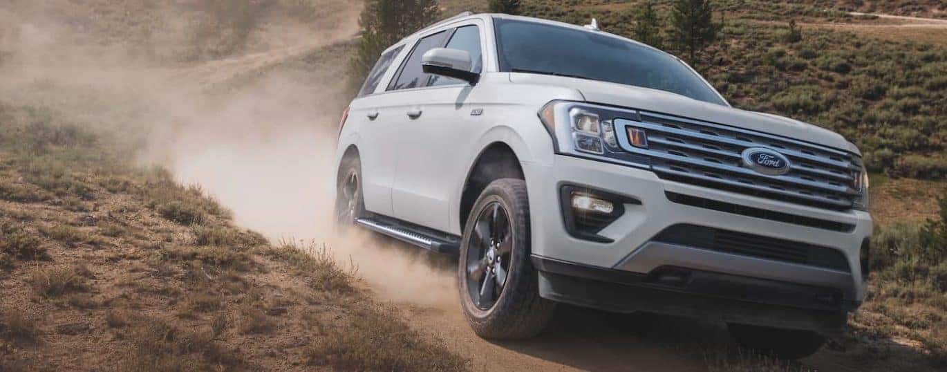 A white 2021 Ford Expedition is shown driving down a dusty path.