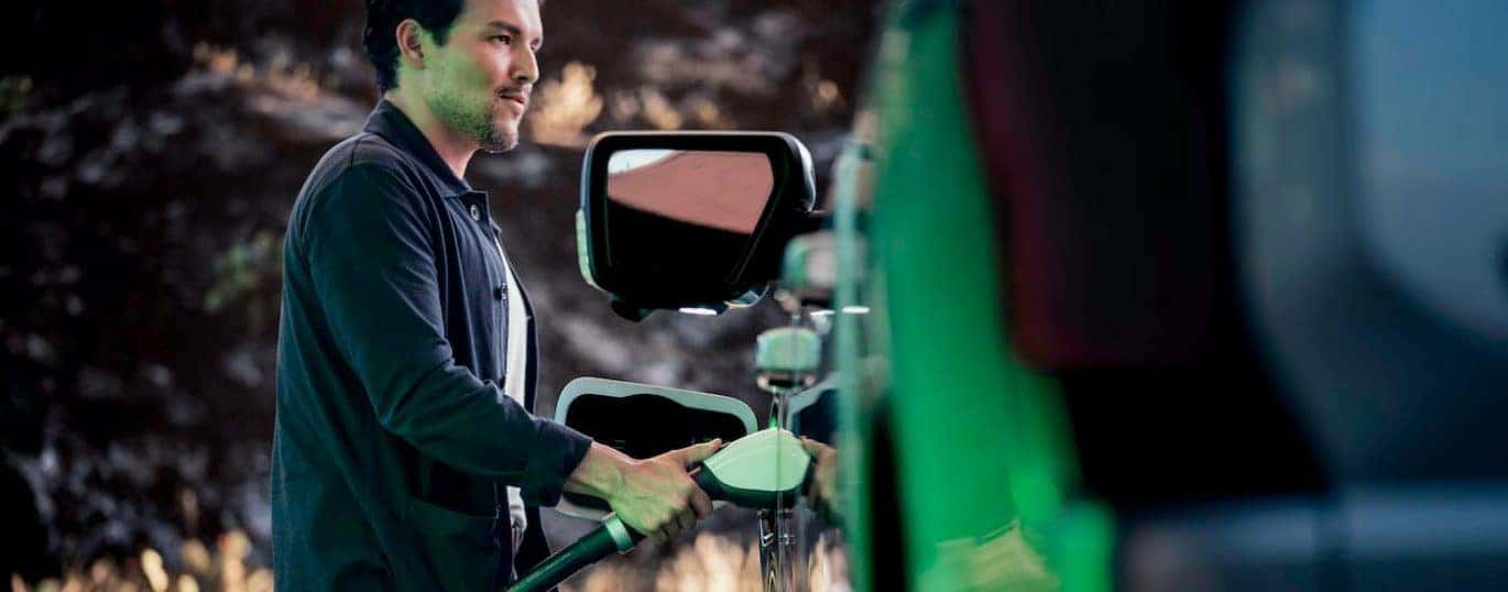 A man is shown charging a 2022 Ford F-150 Lightning after winning a 2022 Ford F-150 Lightning vs 2022 Rivian R1T race.