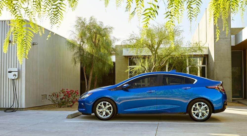A blue 2016 Chevy Volt is shown charging after visiting an Albany used car dealer.