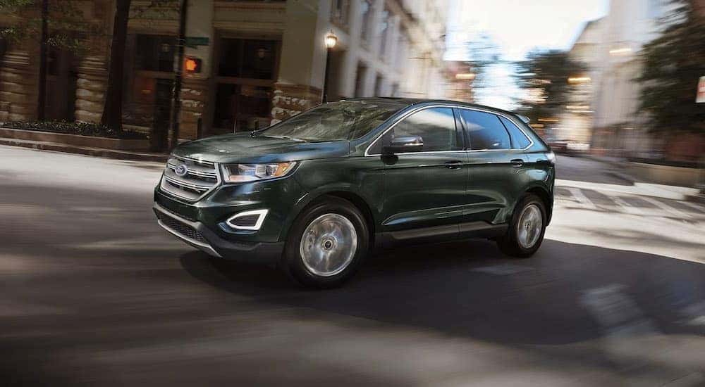 A black 2016 Ford Edge is shown driving on a city street.