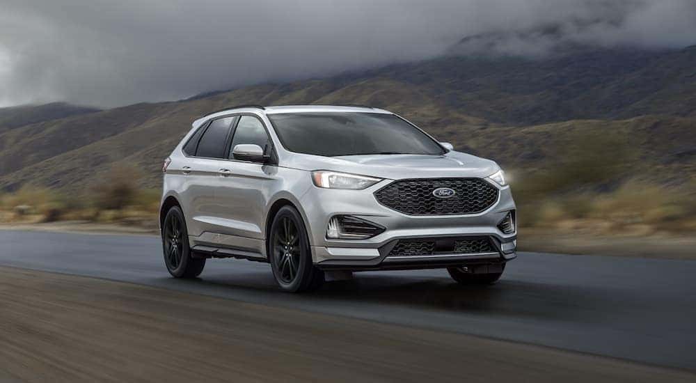 A silver 2019 Ford Edge is shown driving to an Albany used vehicle dealership.