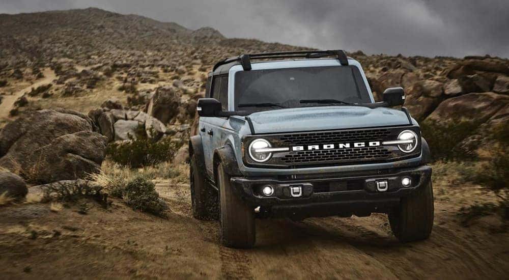 A light blue 2022 Ford Bronco is shown driving on a remote trail.