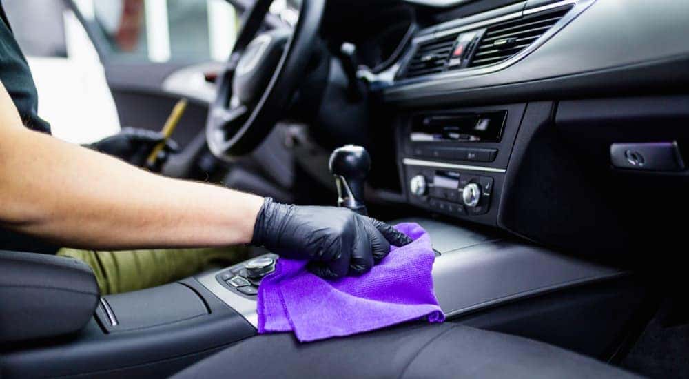 A person is shown cleaning the interior of their car after researching 'how to sell my car.'