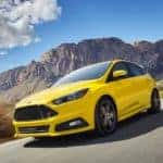 A yellow 2018 Ford Focus ST is shown on an open road after leaving a certified pre-owned Ford dealership.