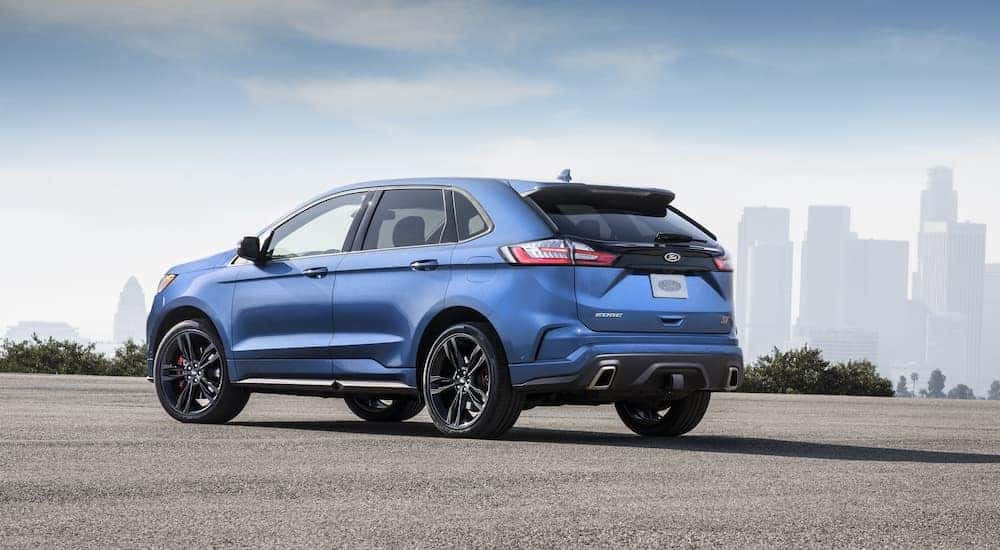 A blue 2019 Ford Edge ST is shown from a rear angle overlooking a city.