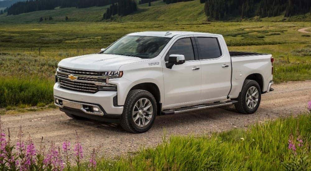 A white 2020 Chevy Silverado 1500 High Country is shown driving down a dirt road.