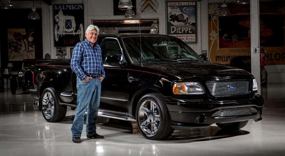 Jay Leno is shown standing next to a black 2000 Ford F-150 Harley Davidson Edition.