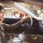 woman with brown hair wearing a dark green jacket sitting in the driver’s seat of a new 2020 Mazda CX-30