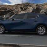 Deep Crystal Blue Mica 2021 Mazda3 hatchback premium trim on black road, brown mountain rocks in background