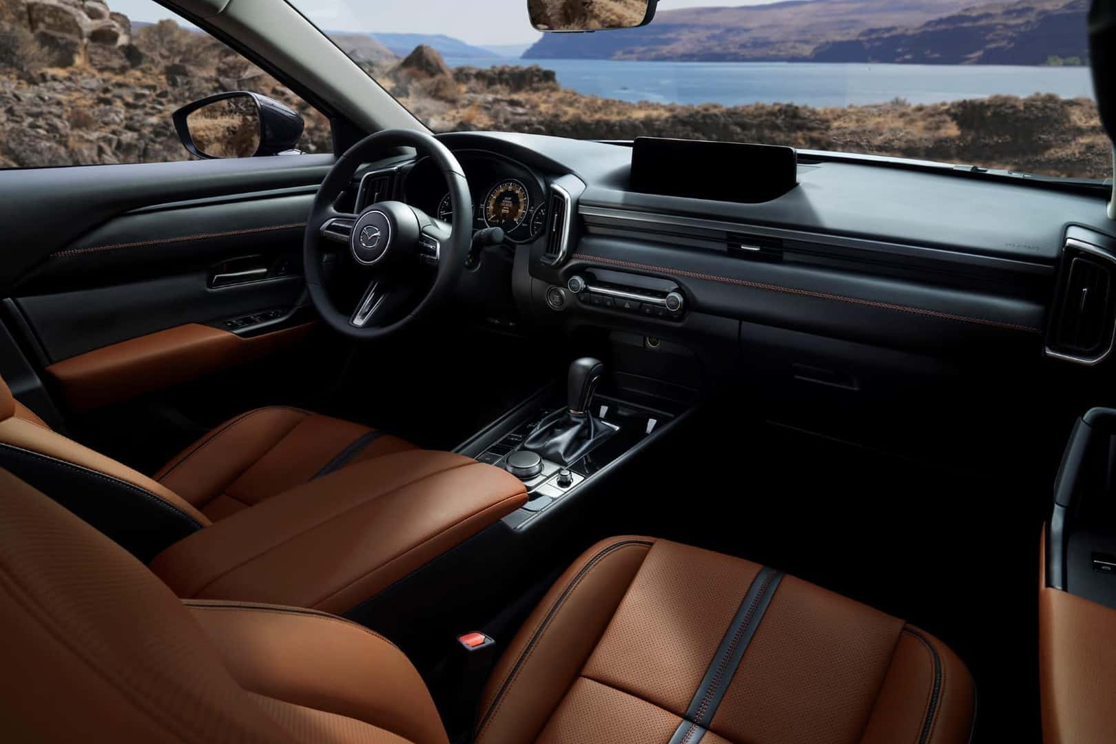 closeup of interior cockpit of the 2023 Mazda CX-50 with brown seats, black dashboard, and steering wheel