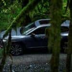 Machine Gray Metallic 2023 CX-50 2.5 Turbo Premium Plus trim driving through green forest