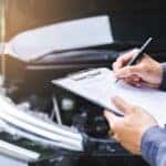 Vehicle safety inspector checking the mechanics and engine under the hood of a vehicle testing the safety