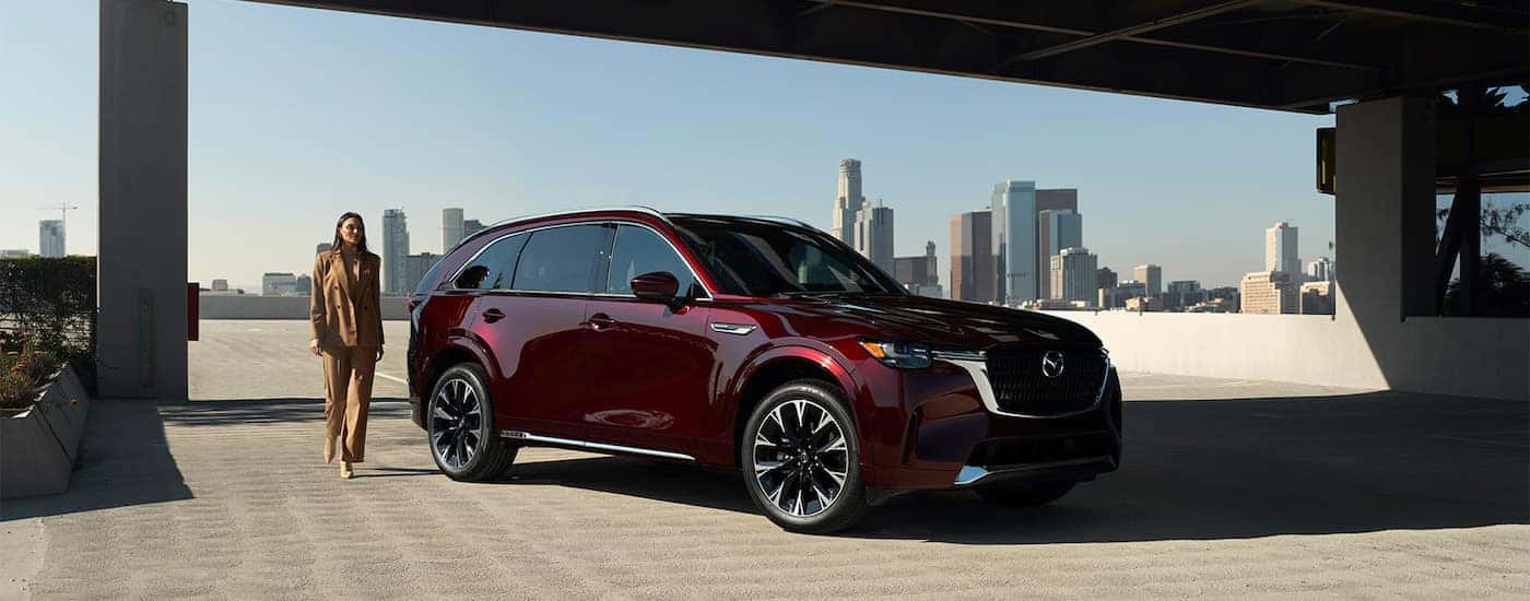 A maroon 2026 Mazda CX-90 from the side after leaving a Mazda dealer.