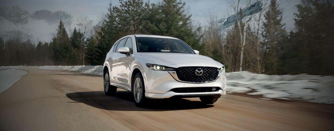 White 2025 Mazda CX-5 driving down a dirt road