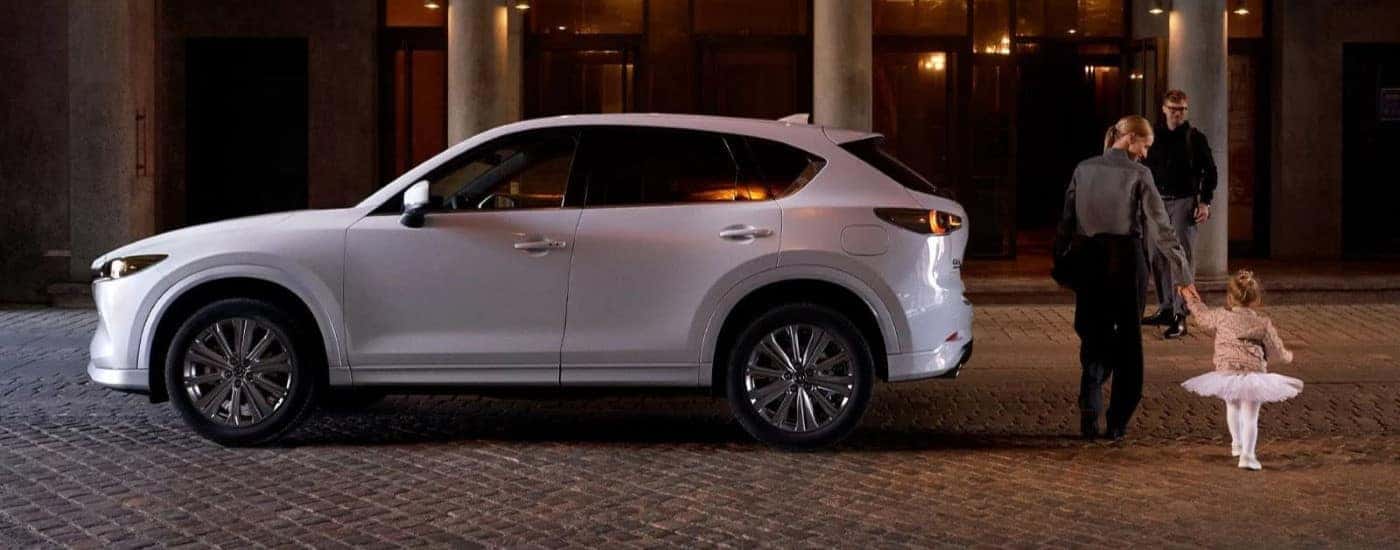 White 2022 Mazda CX-5 parked on the street with a mother and daughter walking toward it