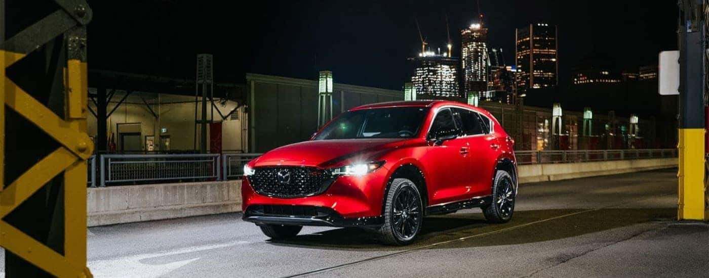 Red 2023 Mazda CX-5 driving through a city at night