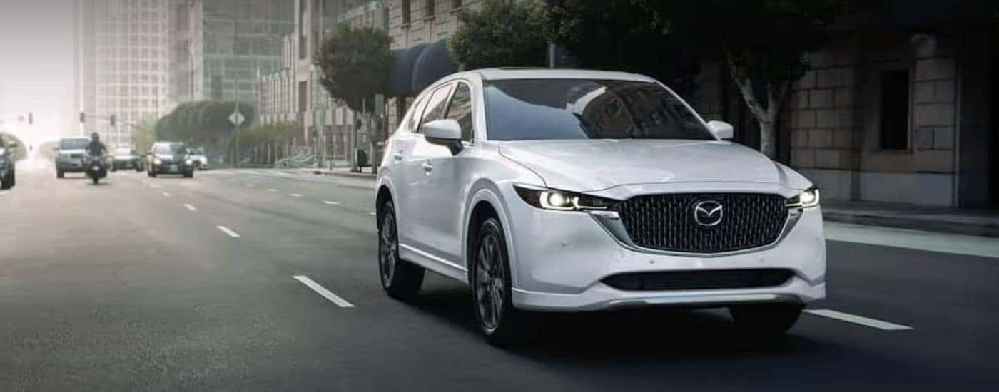 White 2022 Mazda CX-5 driving in front of other vehicles.