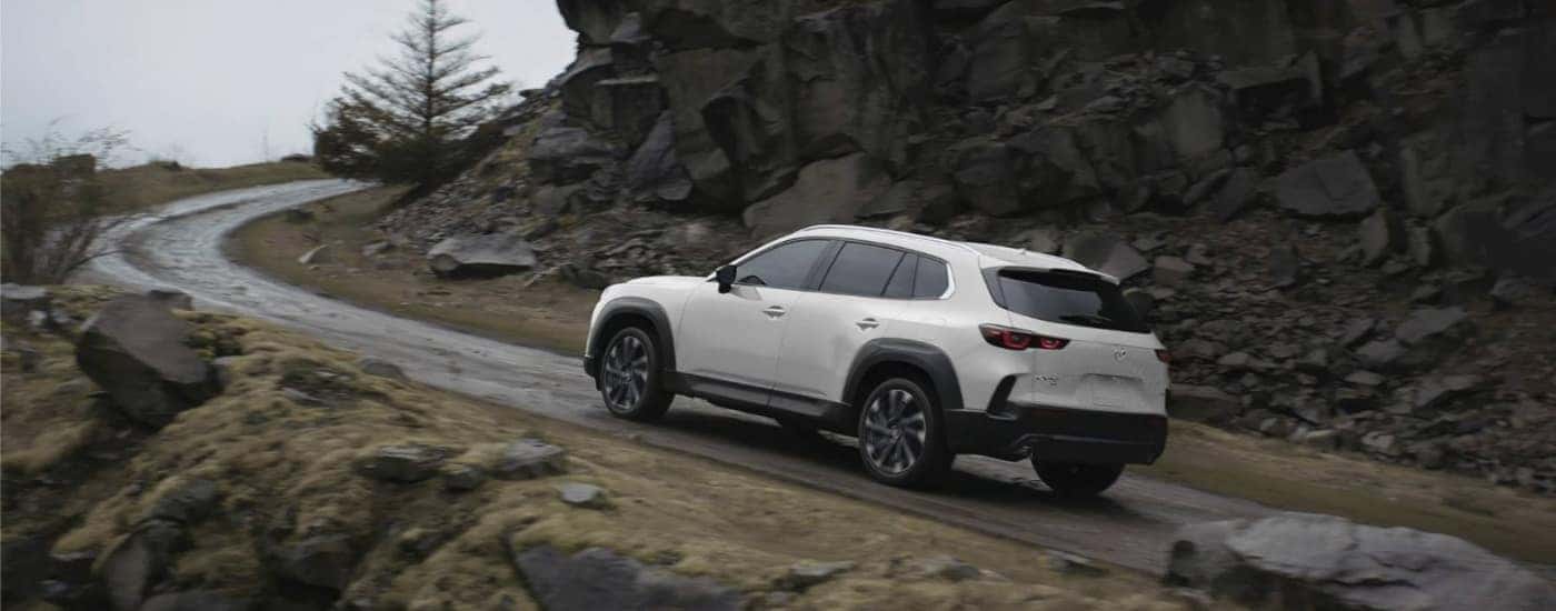 White 2026 Mazda CX-50 Hybrid driving up a mountain road