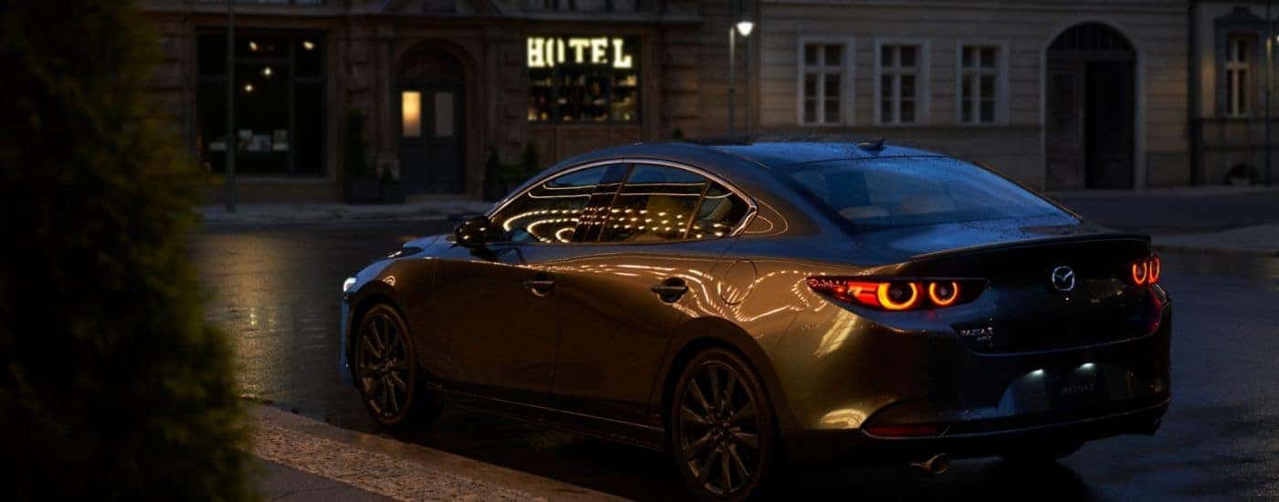 Black 2026 Mazda3 with black alloy wheels parked at night.