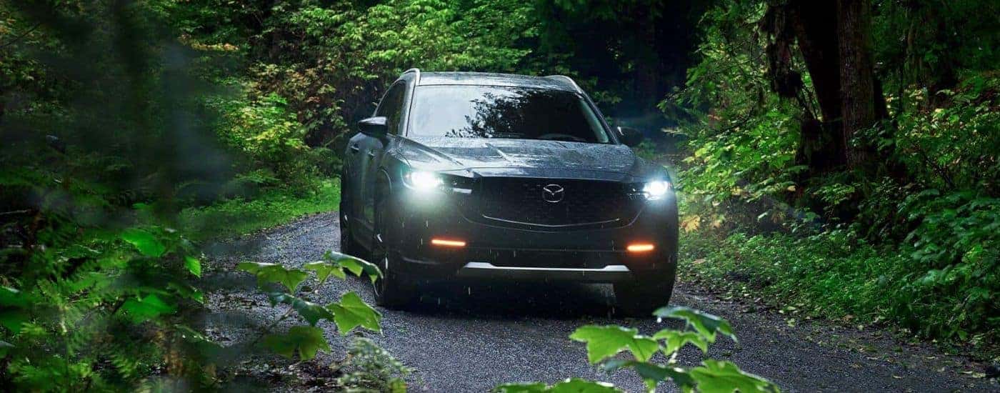 A gray 2023 Mazda CX-50 driving in a forest.