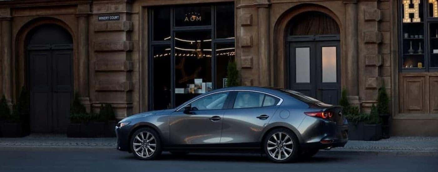 A silver 2026 Mazda3 Sedan parked in a city.