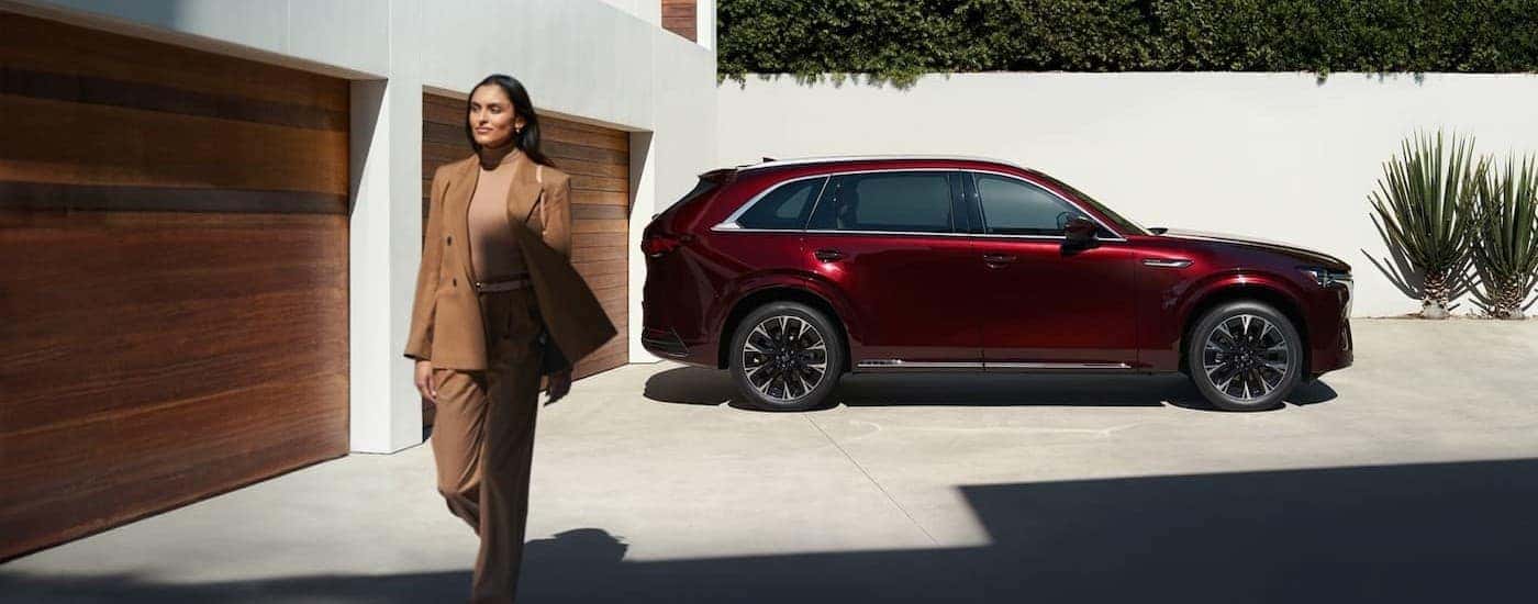 A person walking near a red 2026 Mazda CX-90.